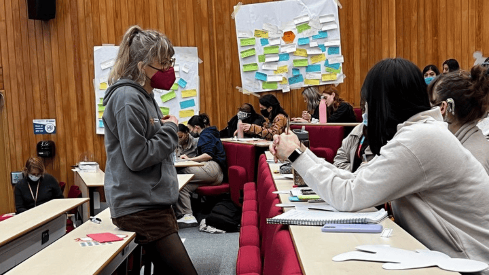 Young woman leading a participatory workshop with diverse attendees in a conference room.