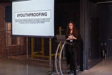 Young woman presenting on heritage crafts and engaging youth in traditional methods.
