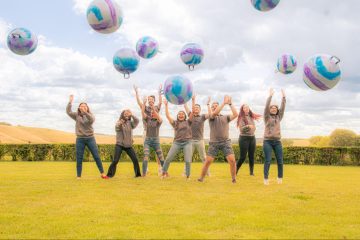Group of young people celebrating with colorful balloons outdoors.