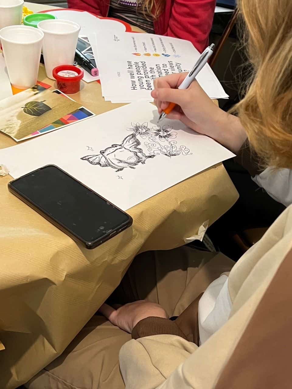 Engaged young person drawing a creative illustration at a youth engagement event.
