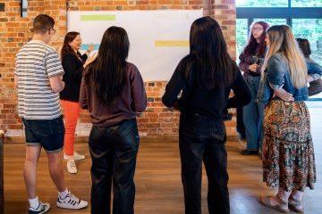 Group of young people participating in a youth hackathon workshop indoors.