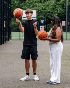 Young man and woman practicing basketball on an outdoor court, promoting youth mental health and act.