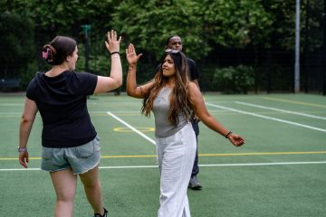 High-five between diverse young women promoting mental health awareness.