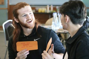 two young men talking to each other with post it notes, discussing what does sport and youth voices mean to the