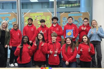 a group of young people wearing red hoodies smiling at the camera after creating Vodafone's global youth safety charter