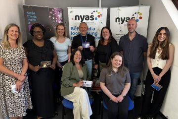 a photo of a group of people standing in a group smiling, they have just successfully embedded youth voice across their organisation