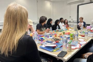 A group of young people working at a table, being trained in recruitment. Youth participation in recruitment at work