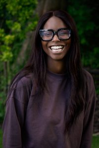Empowered woman smiling outdoors, showcasing confidence and positivity.