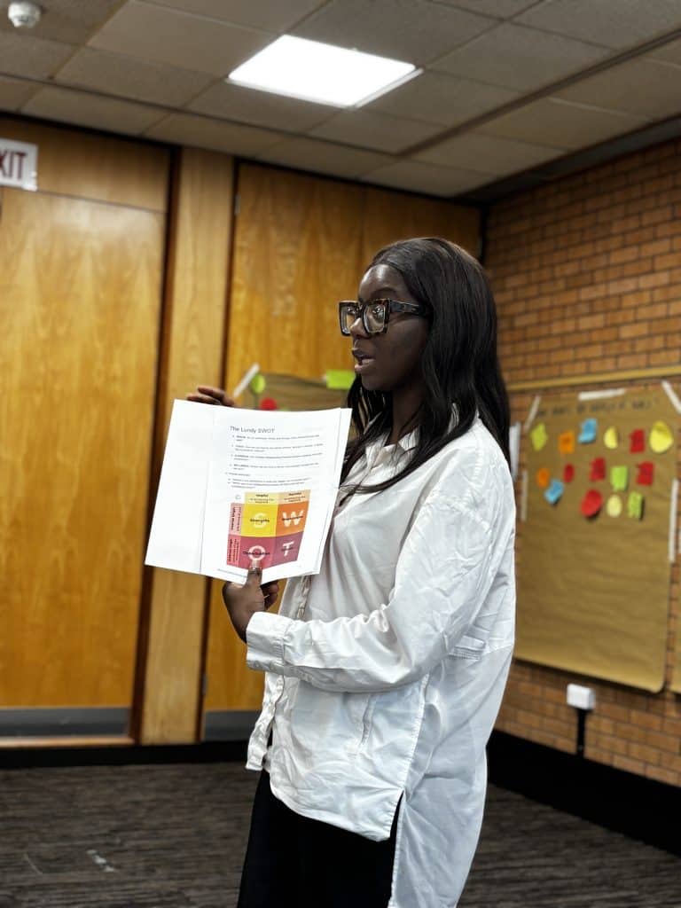 A photo of a woman holding up a SWOT sheet 