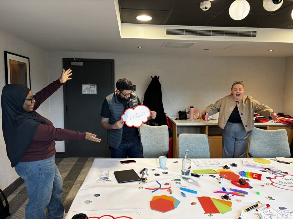 three people laughing around a table as they take part in youth engagement training